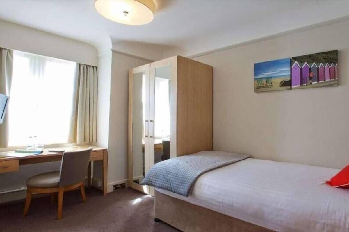 Une chambre d’hôtel avec un lit, un bureau, une chaise et un tableau au mur.