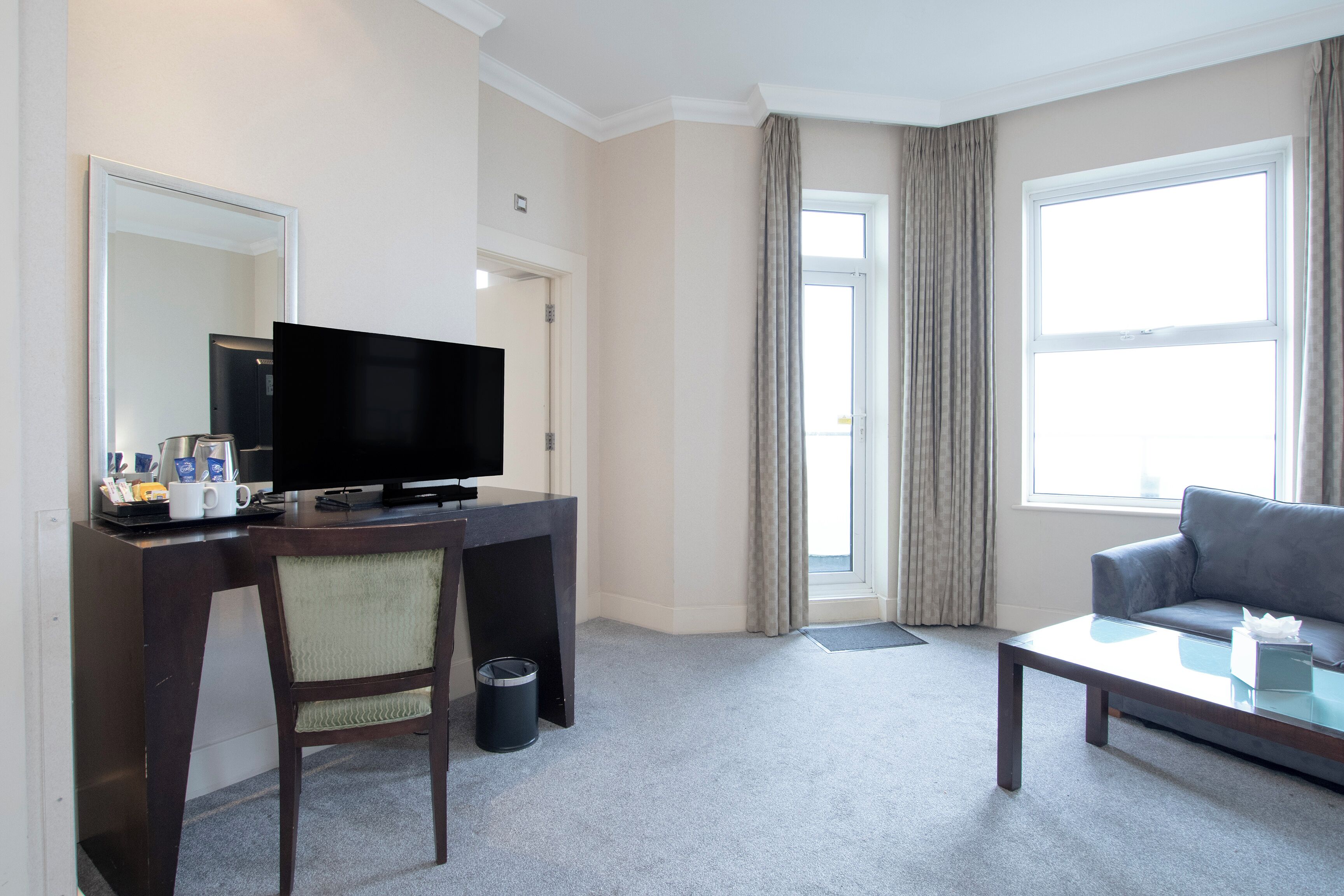 Habitación de hotel con escritorio, televisor, sofá y ventana grande.