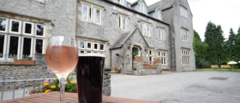A table with two glasses of beverages and a stone building in the background.