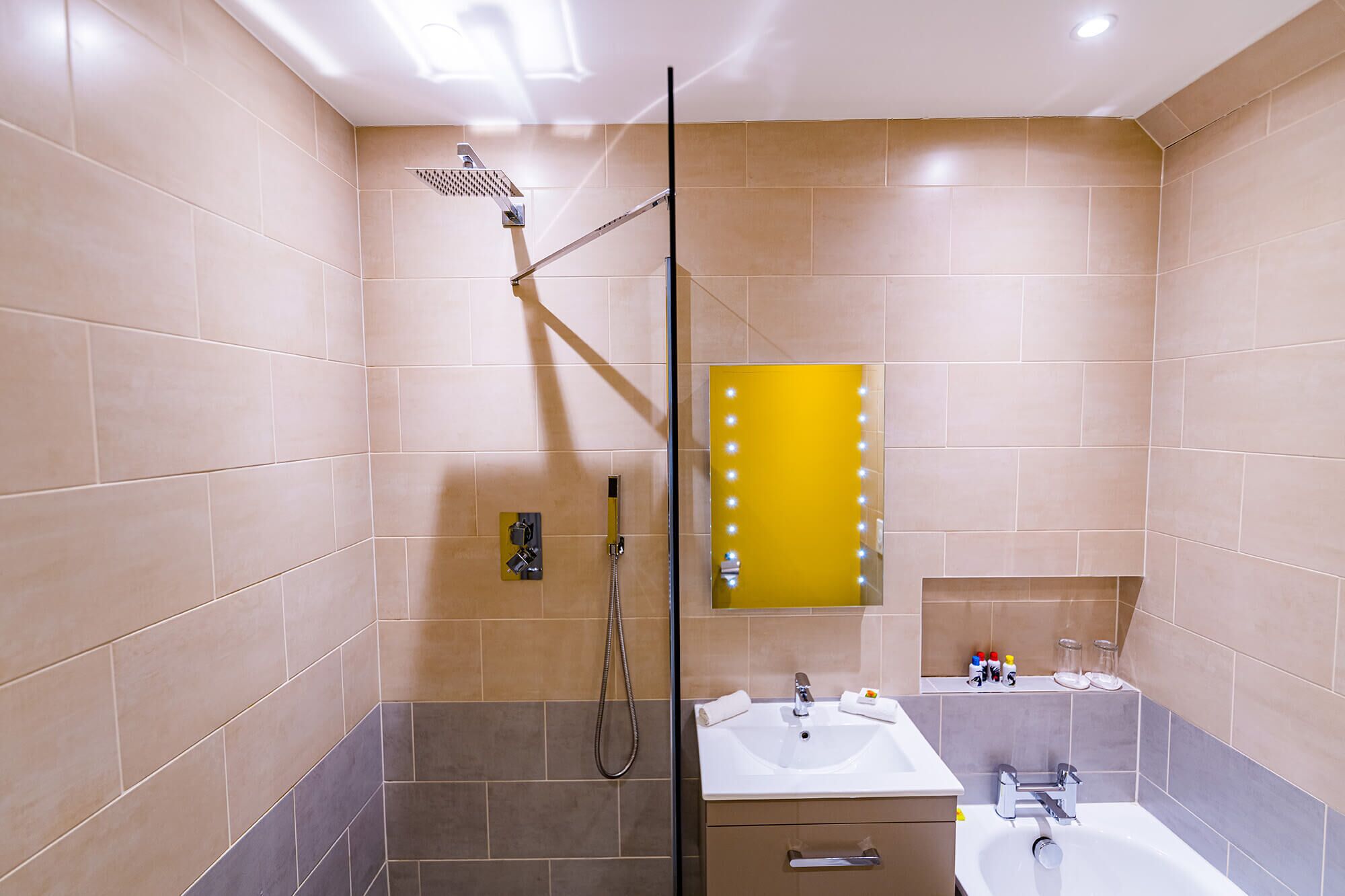 Un baño moderno con ducha envuelta en vidrio, tocador con espejo y bañera.