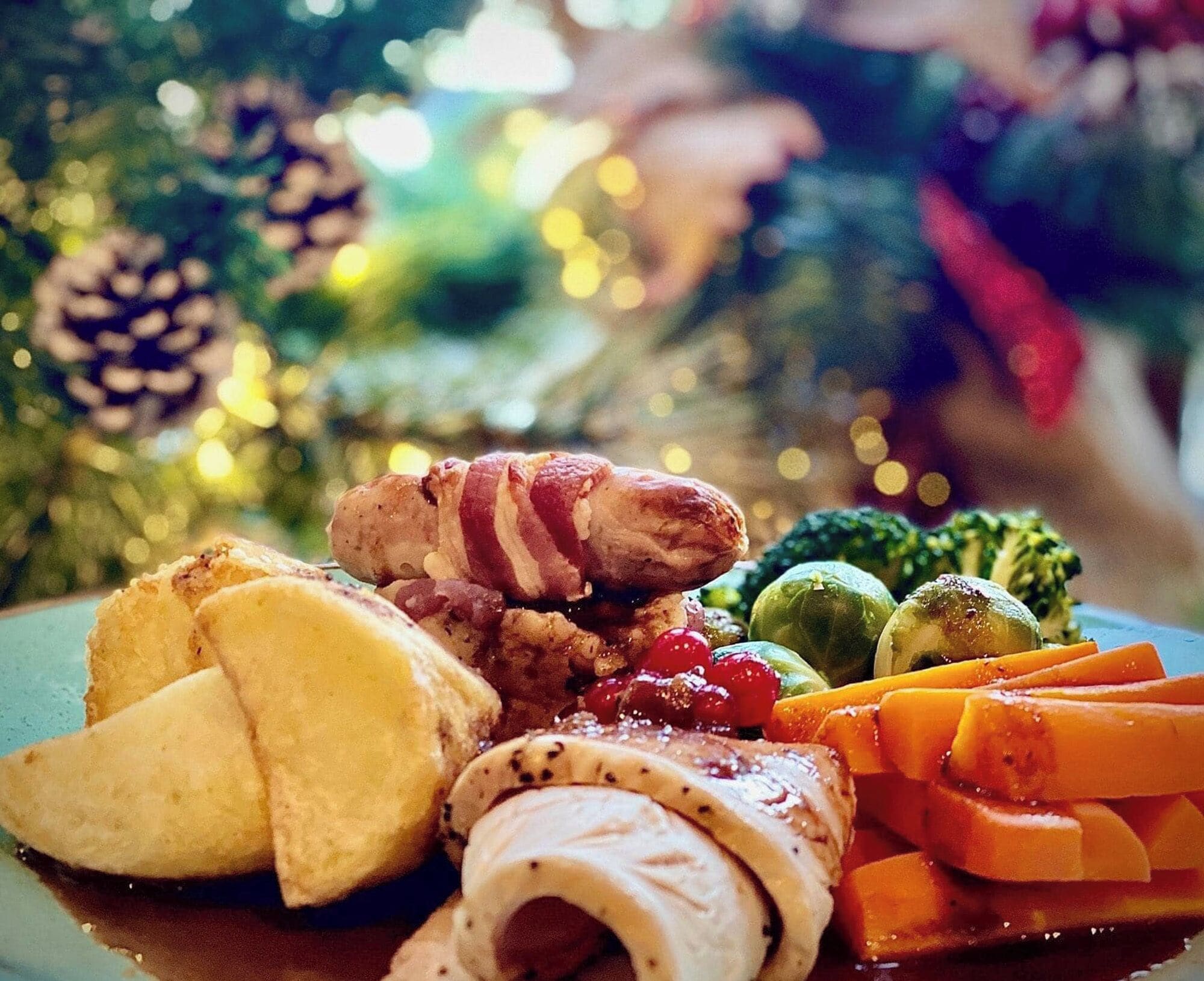 Una comida festiva con varios platos, incluyendo carne, verduras y un pastel enrollado.
