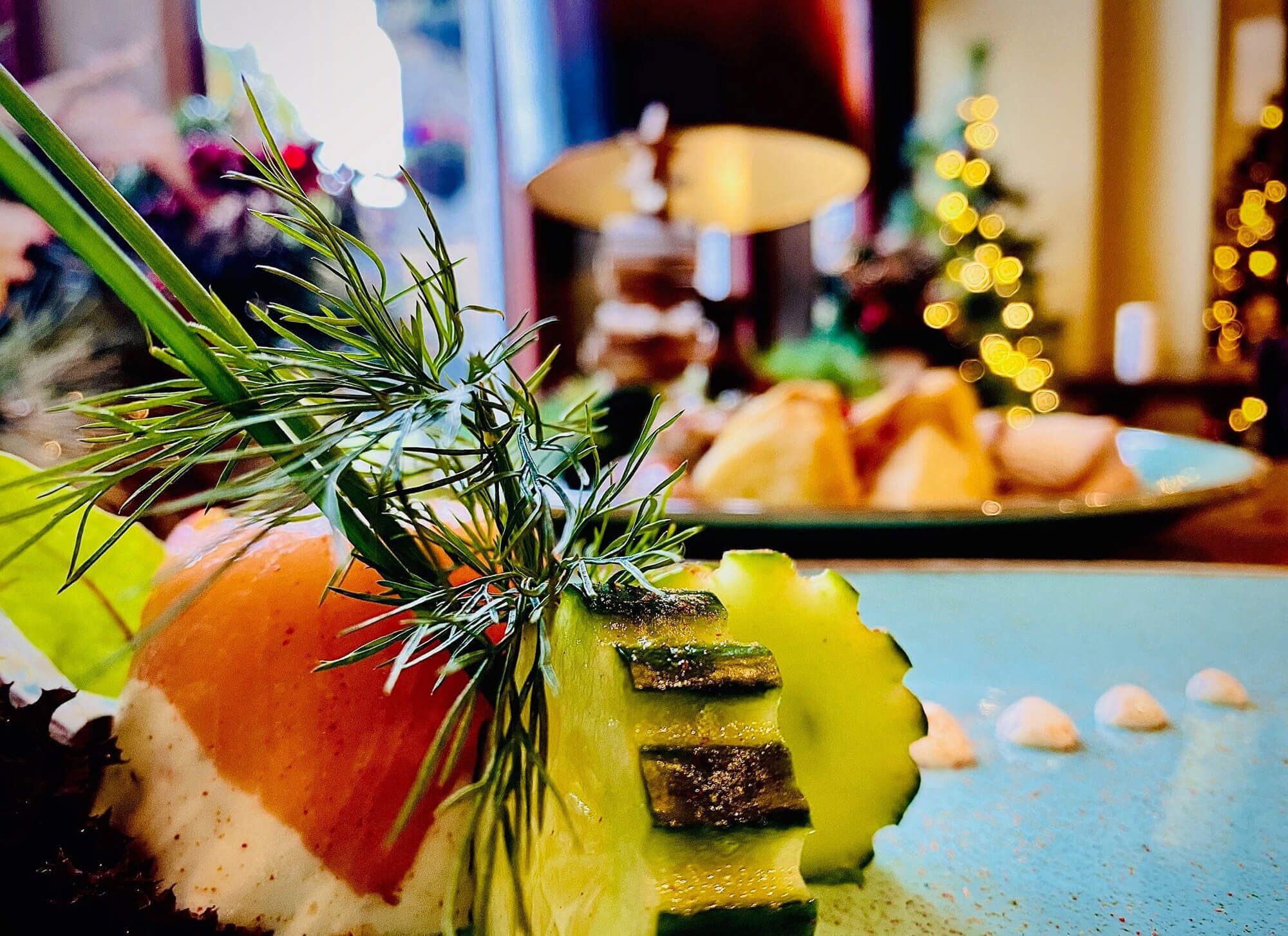 A sushi dish with a decorative garnish of green herbs, served on a blue plate with a blurred background of a dining area.