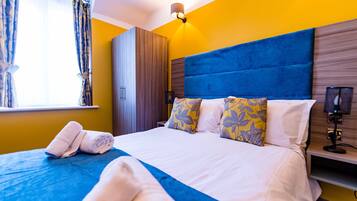 A hotel room with a bed, a wardrobe, a nightstand, and a window with curtains.