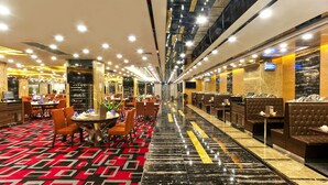 Een hotellobby met een lange gang, zithoeken en een receptiebalie.