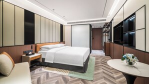 Een moderne hotelkamer met een bed, nachtkastje en een klein tafeltje met een bloevas.