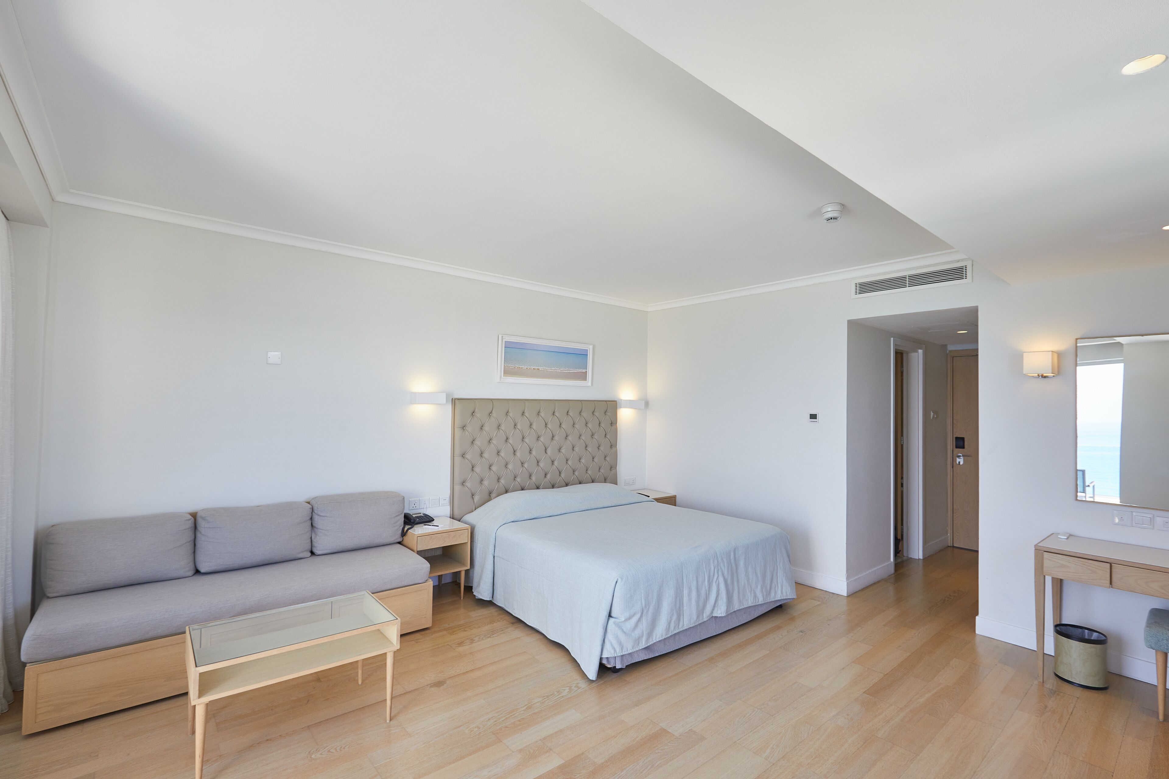 Et moderne soveværelse med seng, sofa, natbord, skrivebord og spejl.