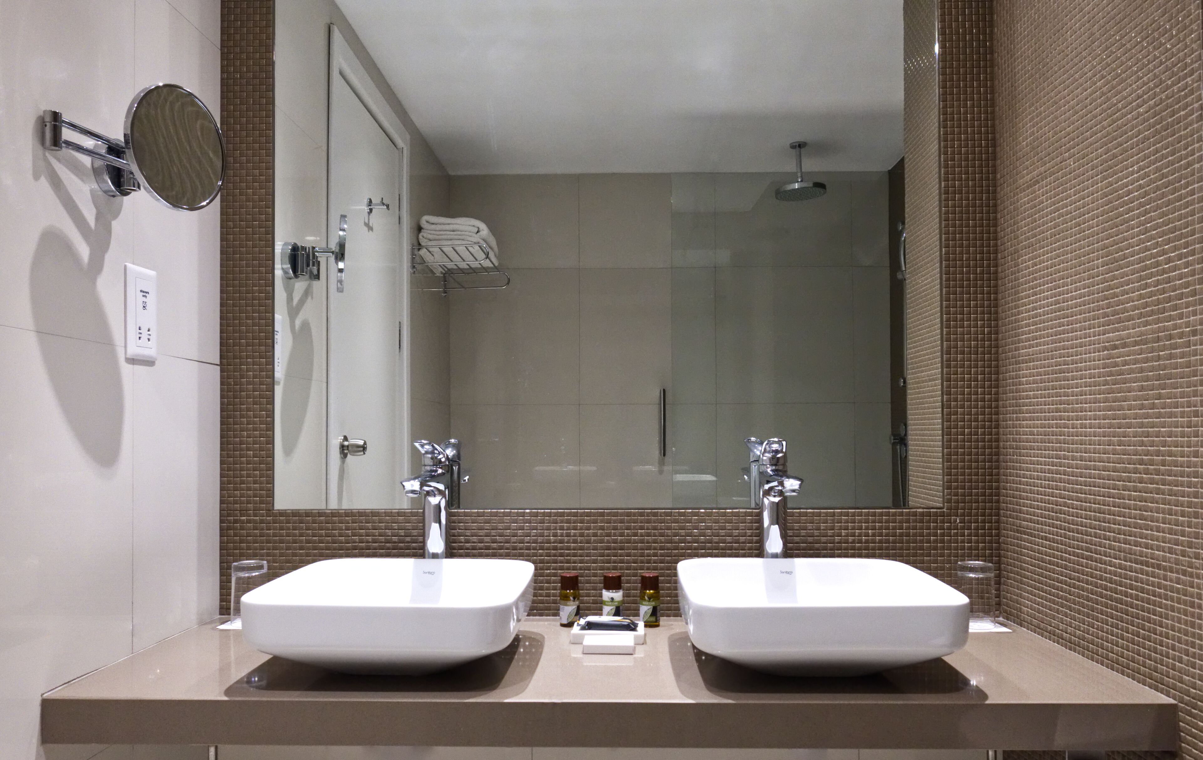 Une salle de bain moderne avec deux lavabos, un grand miroir et un espace douche.