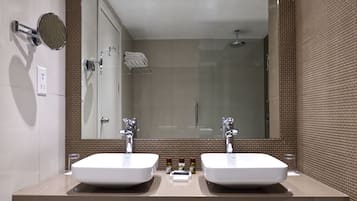 Une salle de bain moderne avec deux lavabos, un grand miroir et un espace douche.