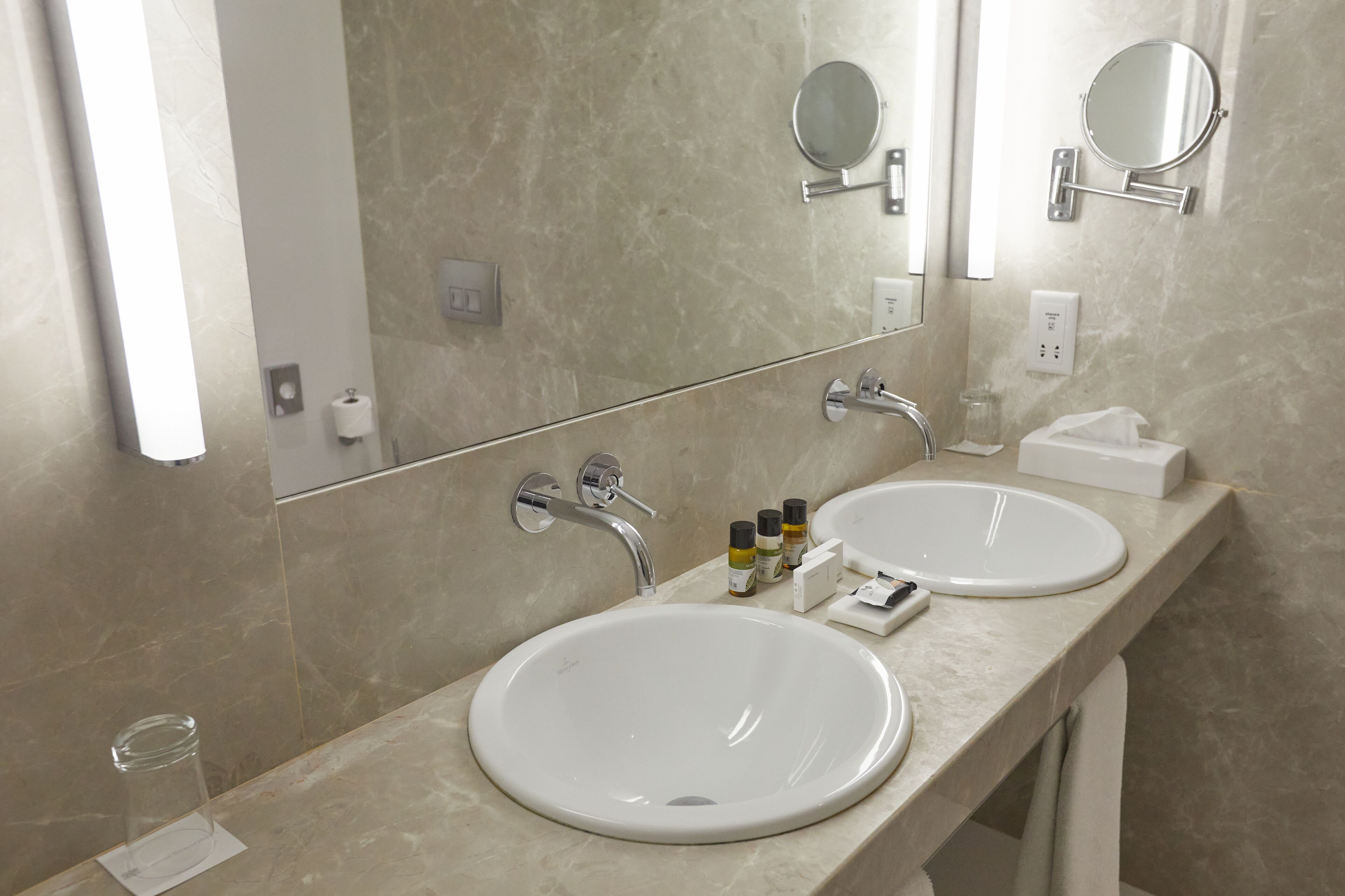 Een badkamer met twee wasbakken, een spiegel en toiletartikelen.
