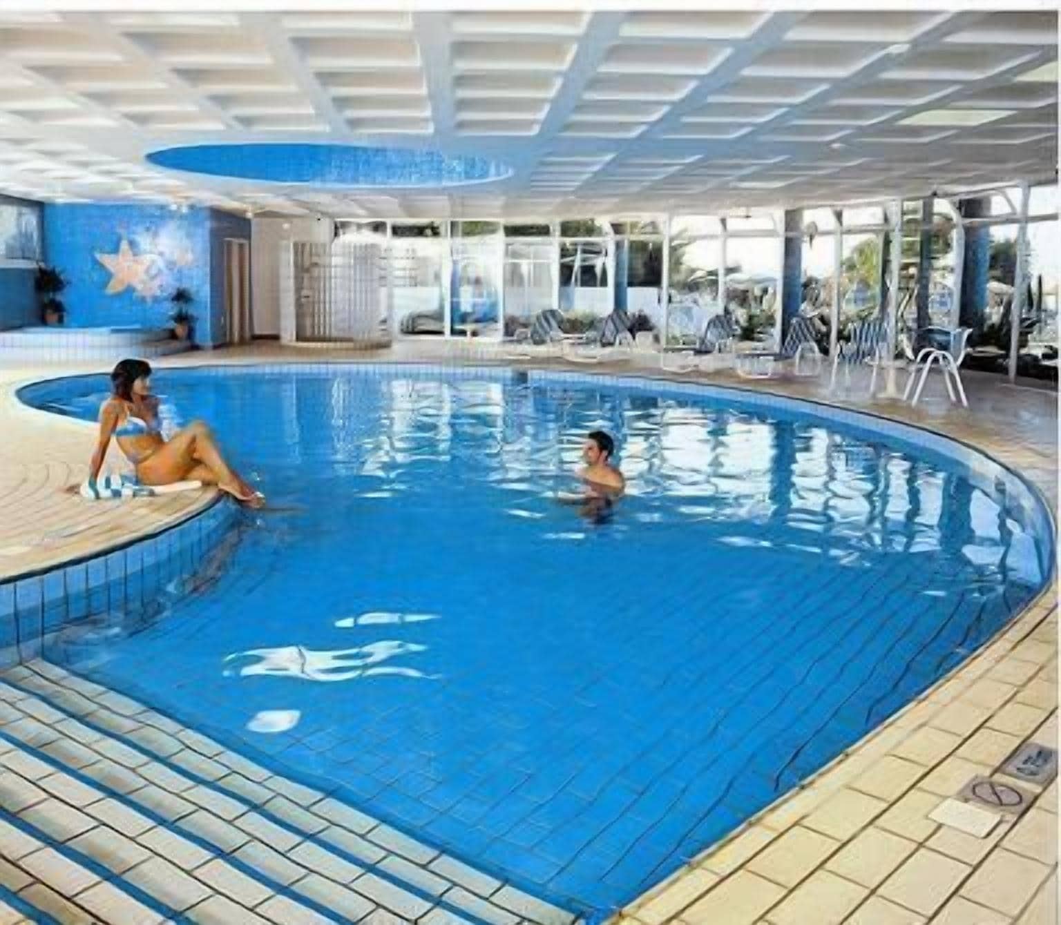 An indoor swimming pool with tiled walls and a curved design.