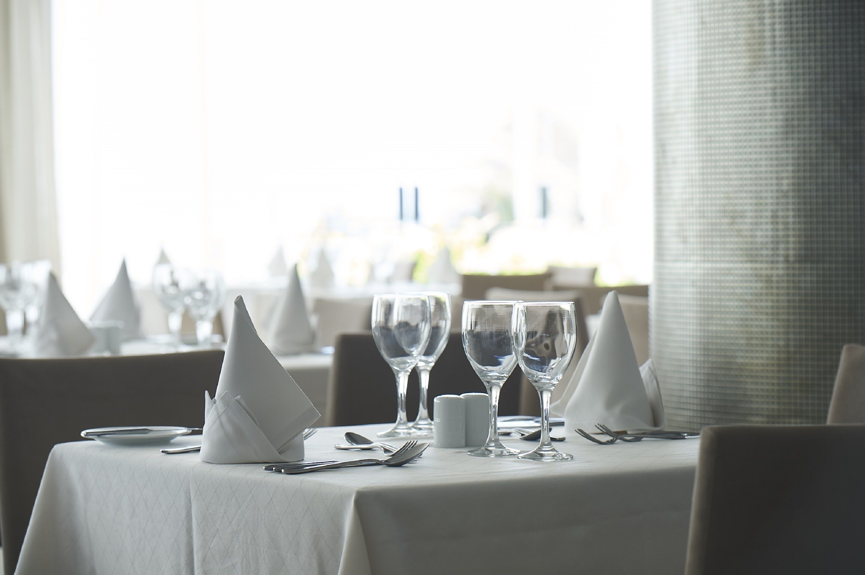 A table set for dining with white tablecloth, napkins, and clear glassware.