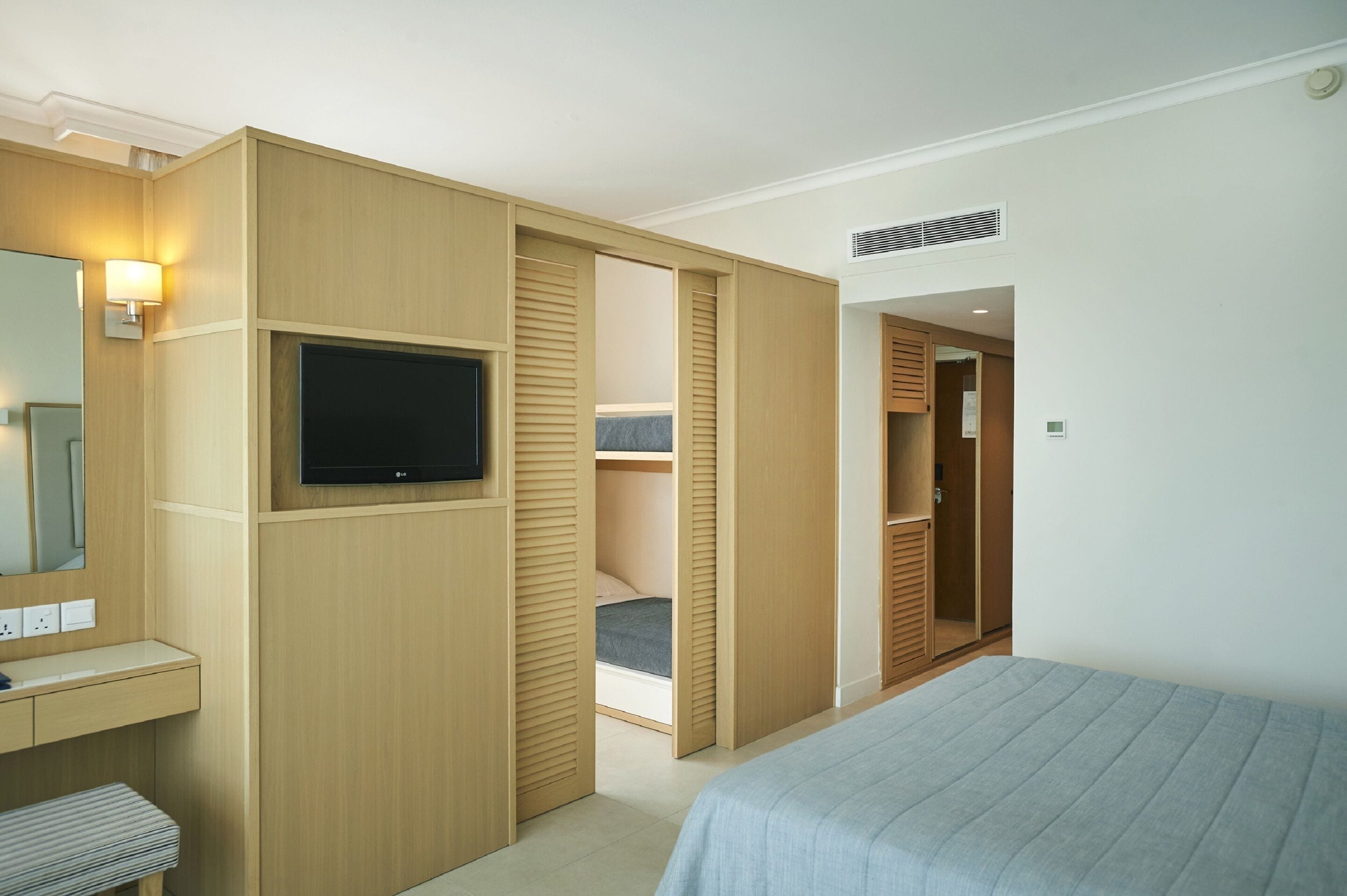 Et moderne hotelværelse med seng, tv, skrivebord og walk-in closet.