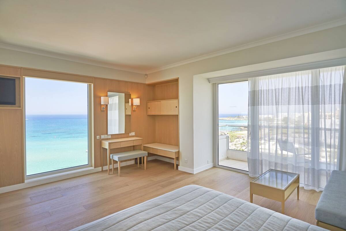 Une chambre d’hôtel avec une grande fenêtre, un lit, un bureau et une chaise.