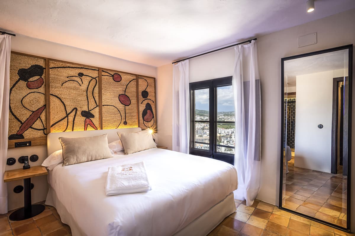 Ein Hotelzimmer mit einem großen Bett, Blick auf die Stadt und modernem Design.