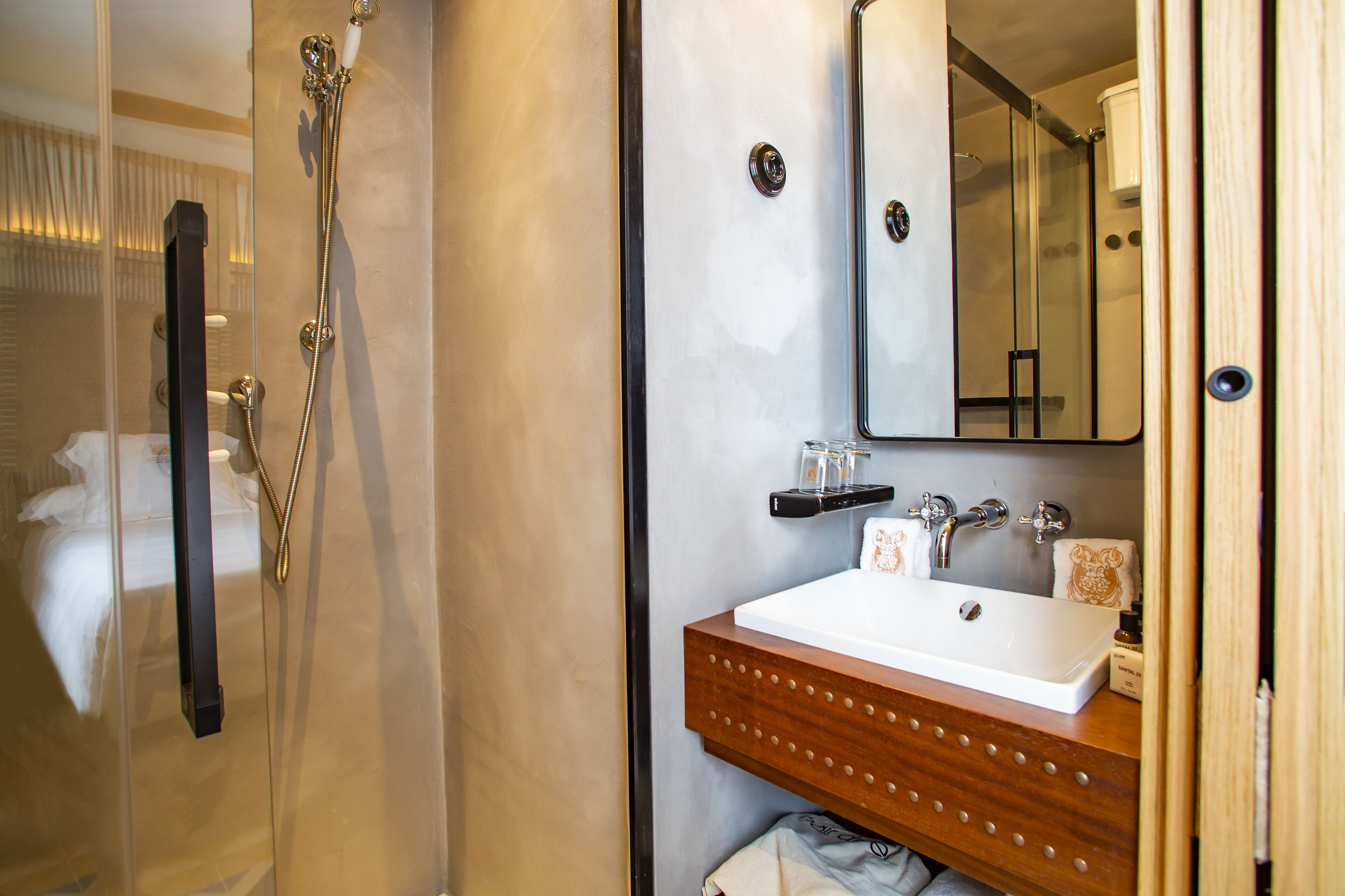 A bathroom with a glass shower enclosure, a wooden vanity with a white sink, and a mirror above the sink.