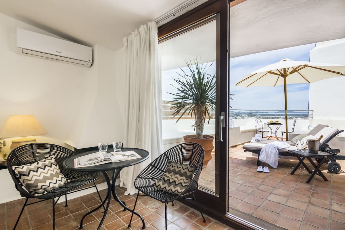 Ein Balkon mit Tisch, Stühlen, einem Blumentopf und einem Sonnenschirm.