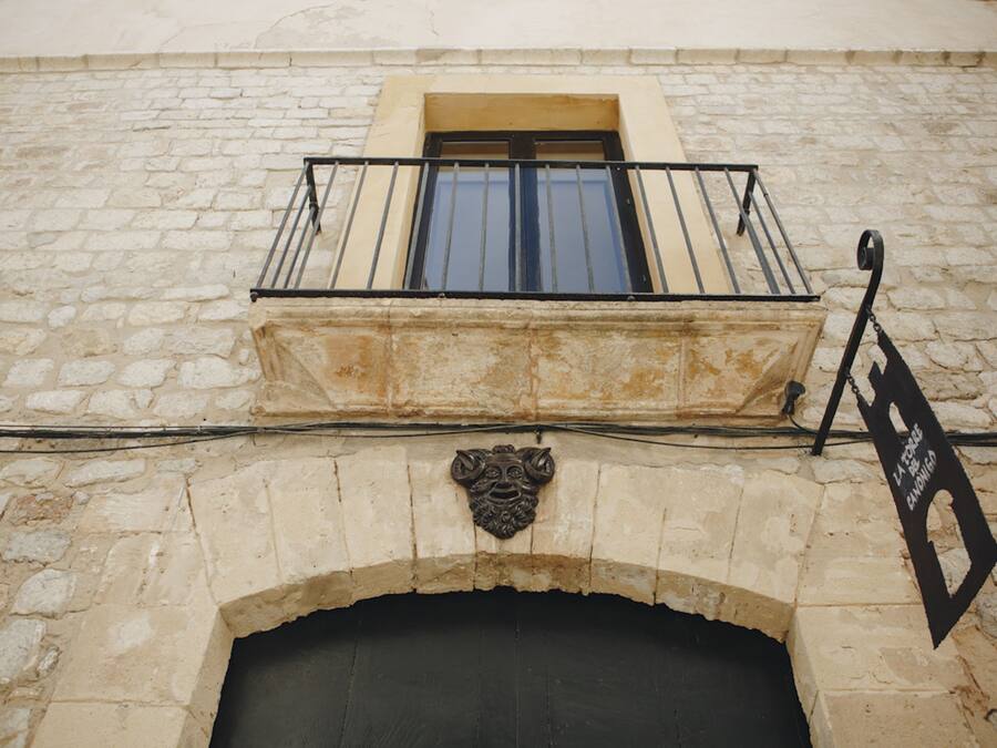 A stone building with a balcony and a sign.