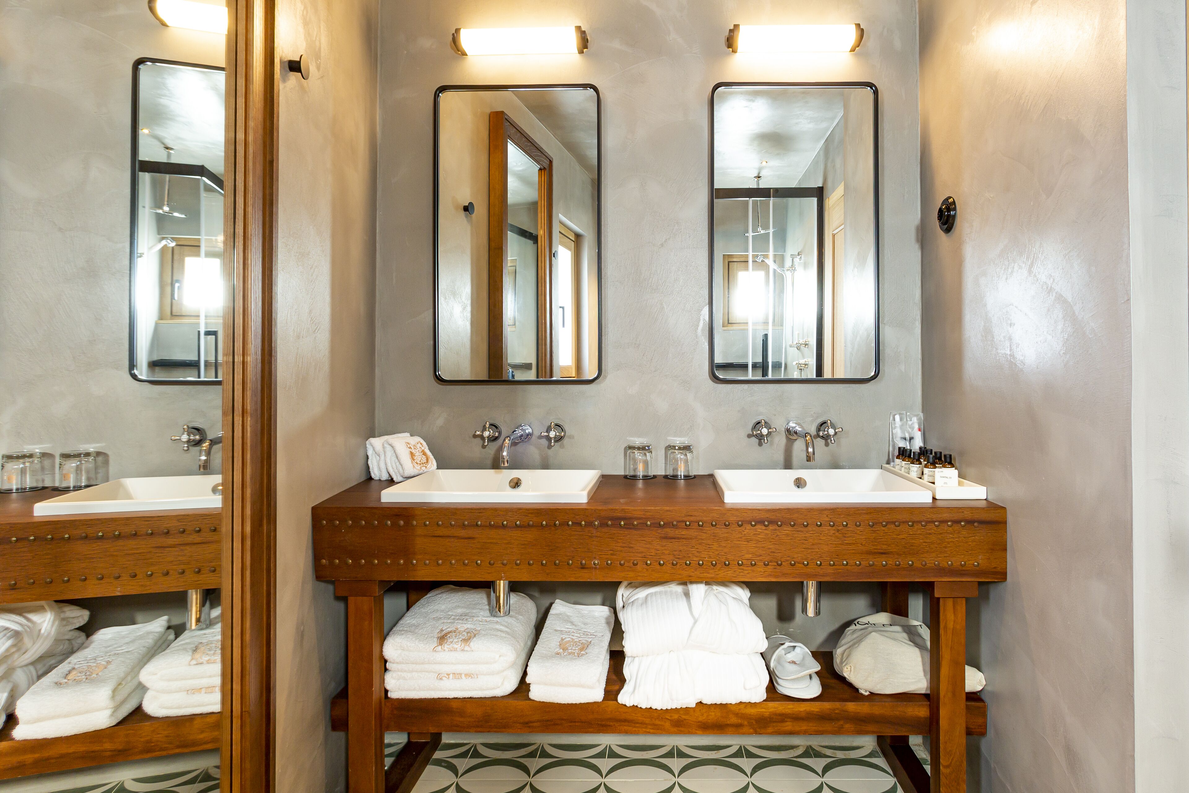 A bathroom with two sinks, mirrors, and a wooden vanity with towels.