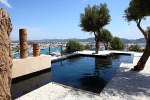 A swimming pool with a view of the sea and distant cityscape.