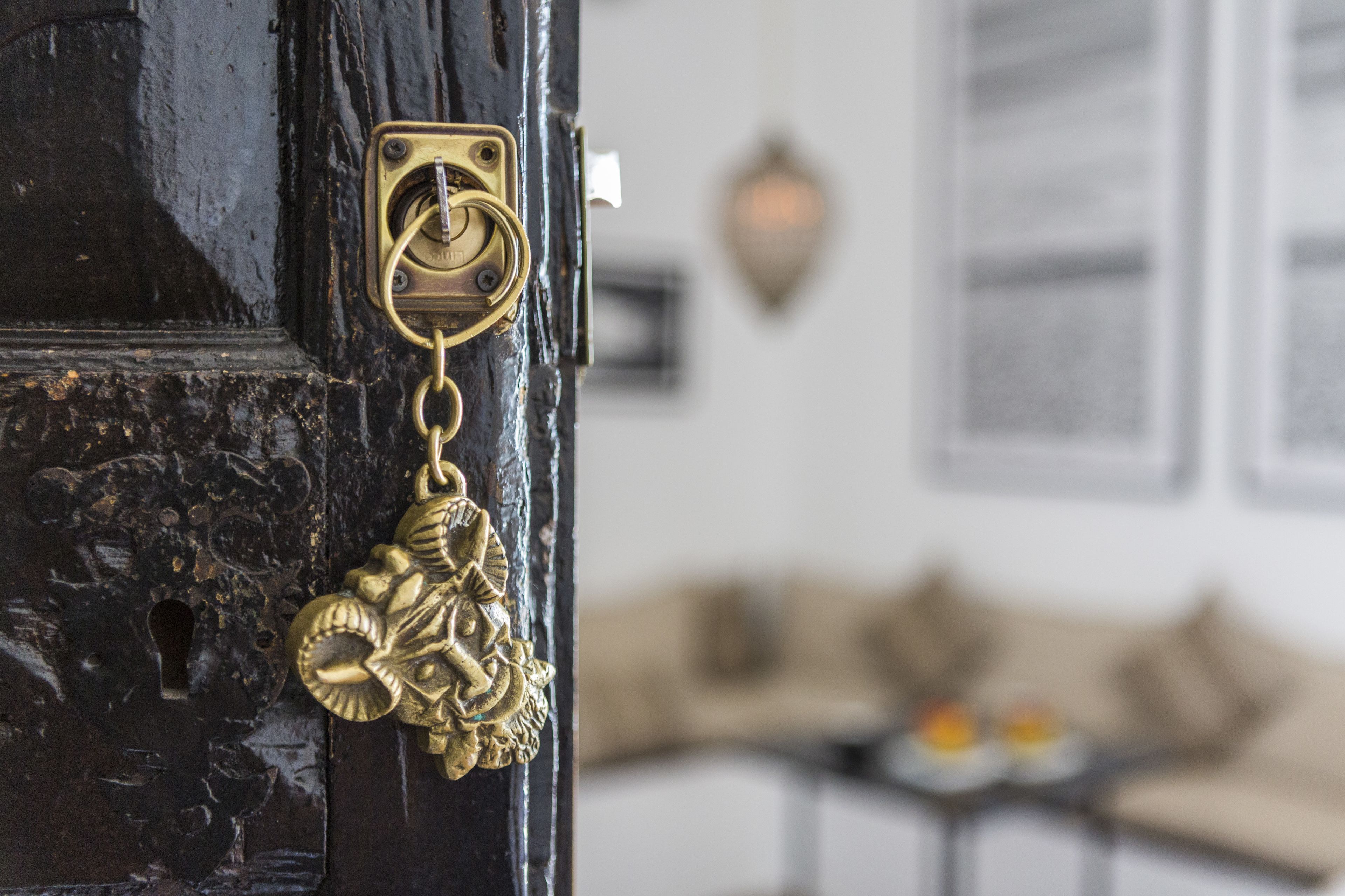 Primer plano de un llamador de latón con diseño decorativo, una cerradura y un aplique de pared al fondo.