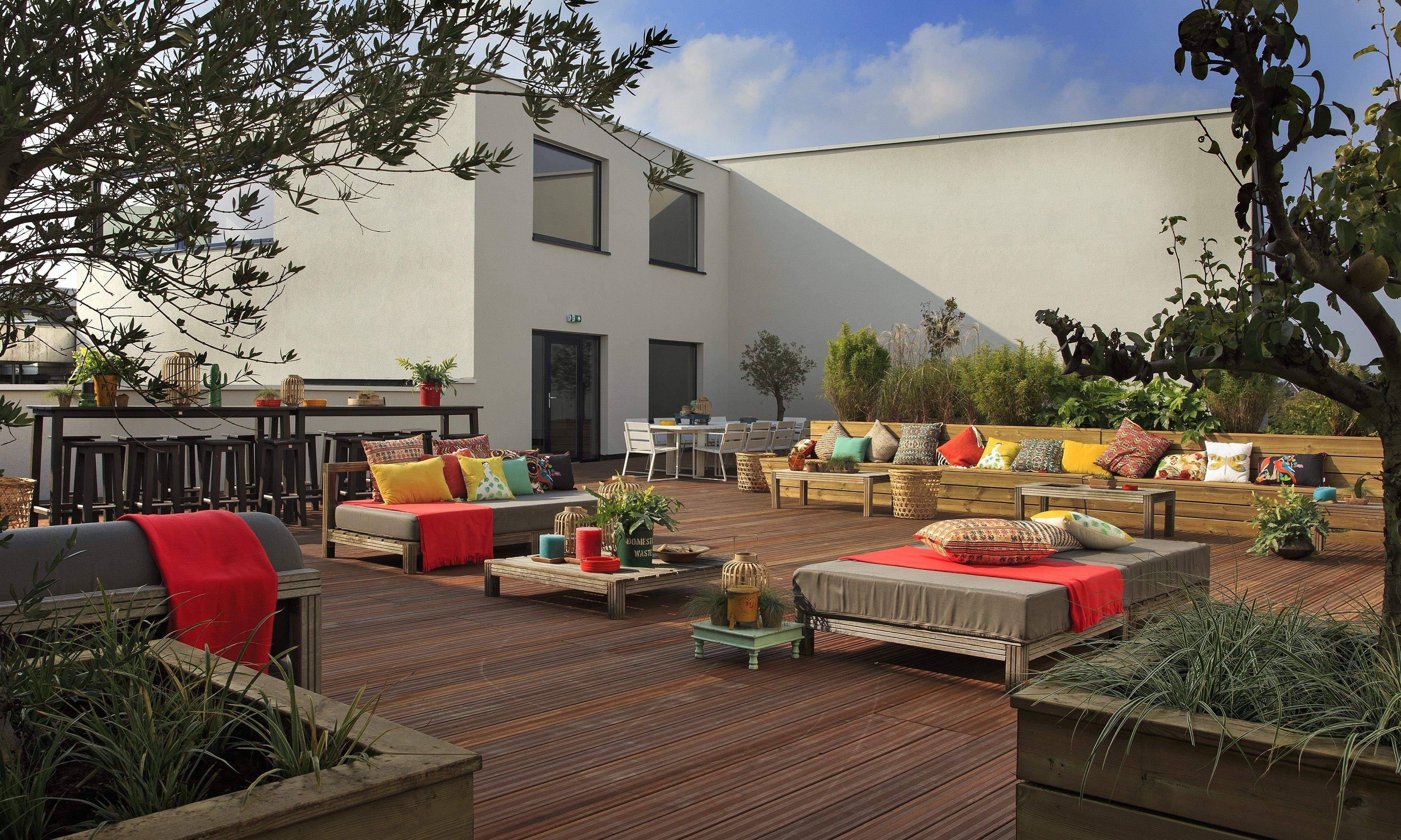An outdoor patio with wooden furniture, a dining area, and potted plants.