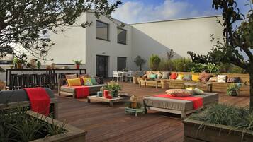 An outdoor patio with wooden furniture, a dining area, and potted plants.
