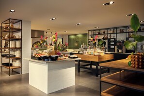 A modern kitchen with white brick walls, wooden shelves, and a central island. - Van der Valk Hotel Sassenheim - Leiden (Sassenheim)