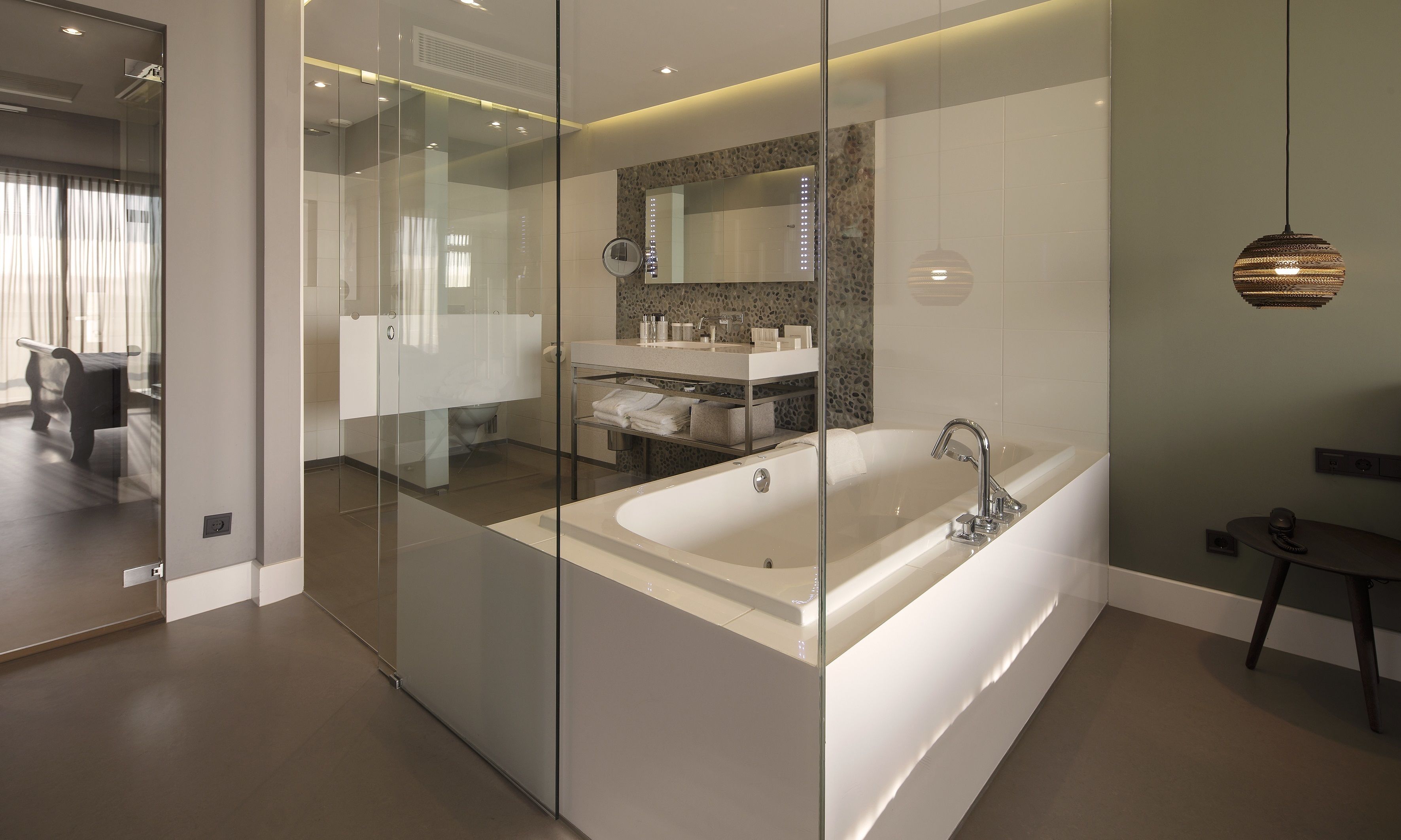 Een moderne badkamer met een glazen douchecabine, een vrijstaand bad en een wastafel met spiegel.