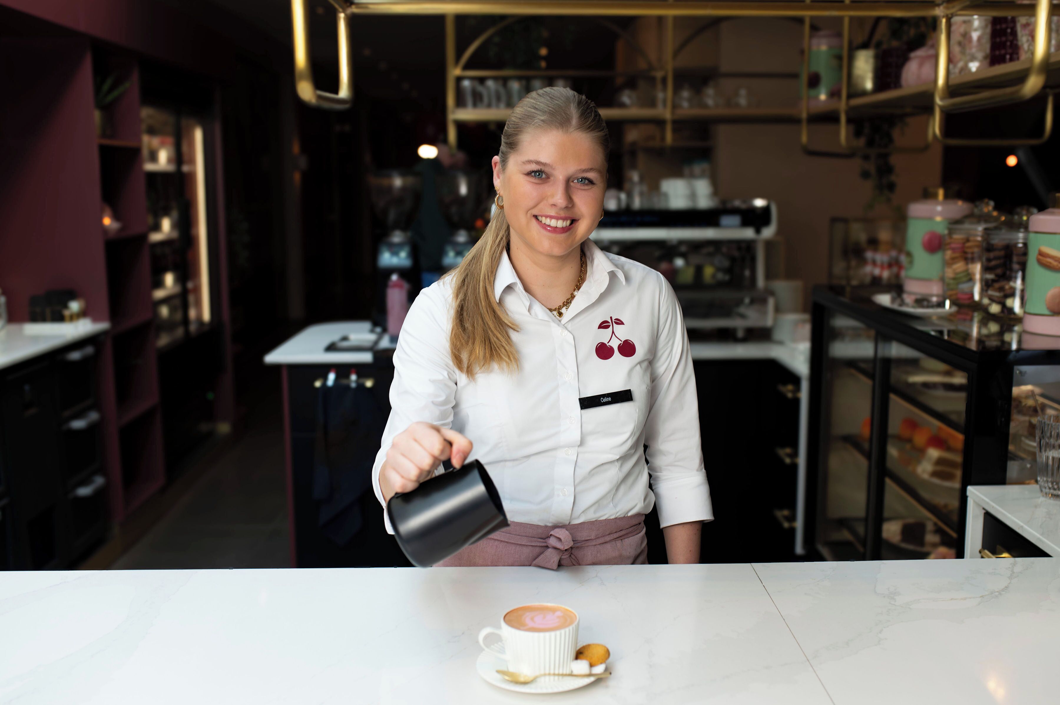 A person pouring a drink into a cup at a bar counter.