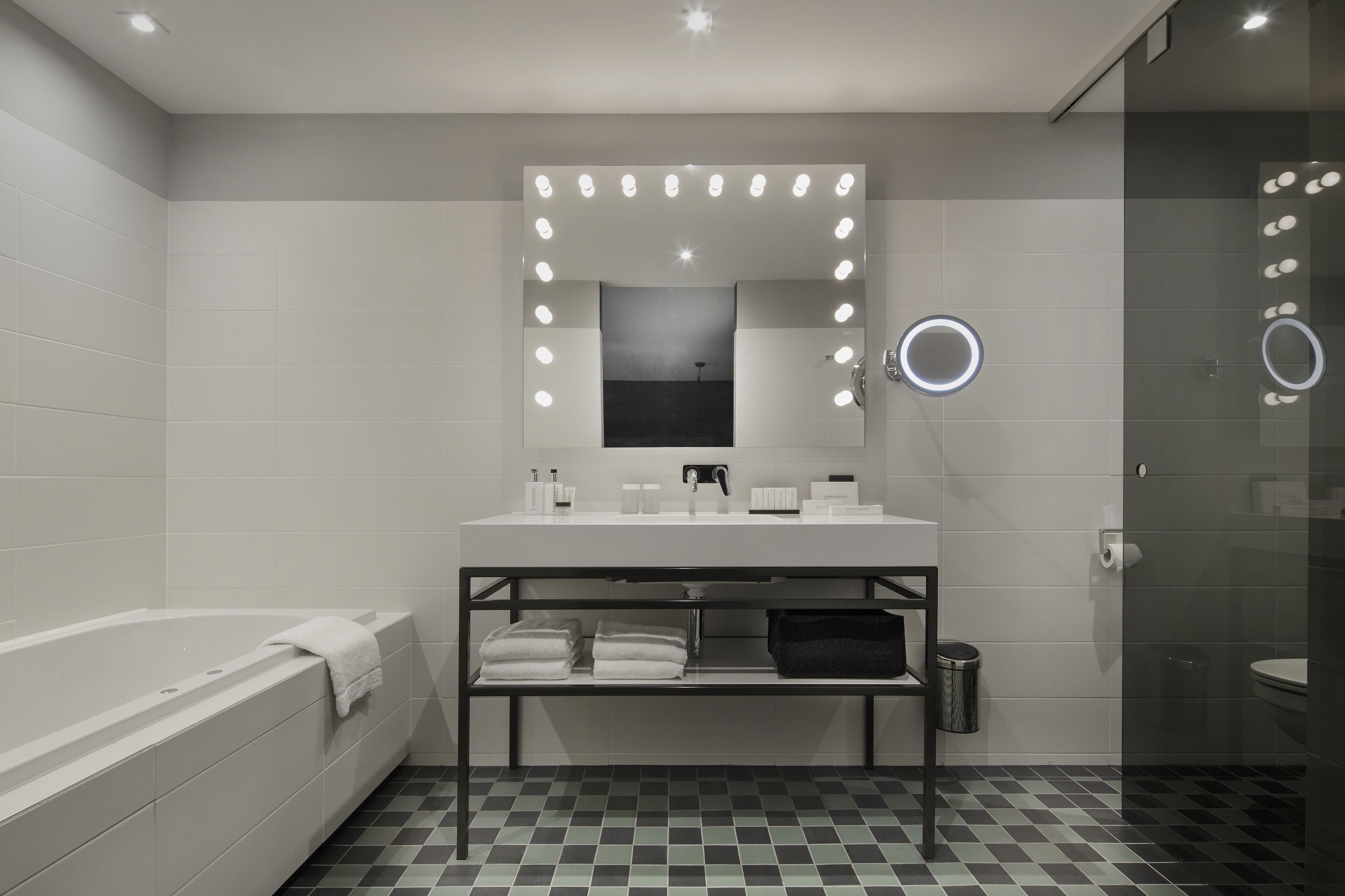 Une salle de bain moderne avec un grand miroir, un meuble-lavabo et une baignoire.