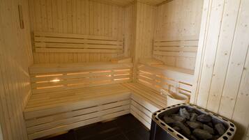 Eine Sauna mit Holzbänken und einem Mülleimer voller Steine.