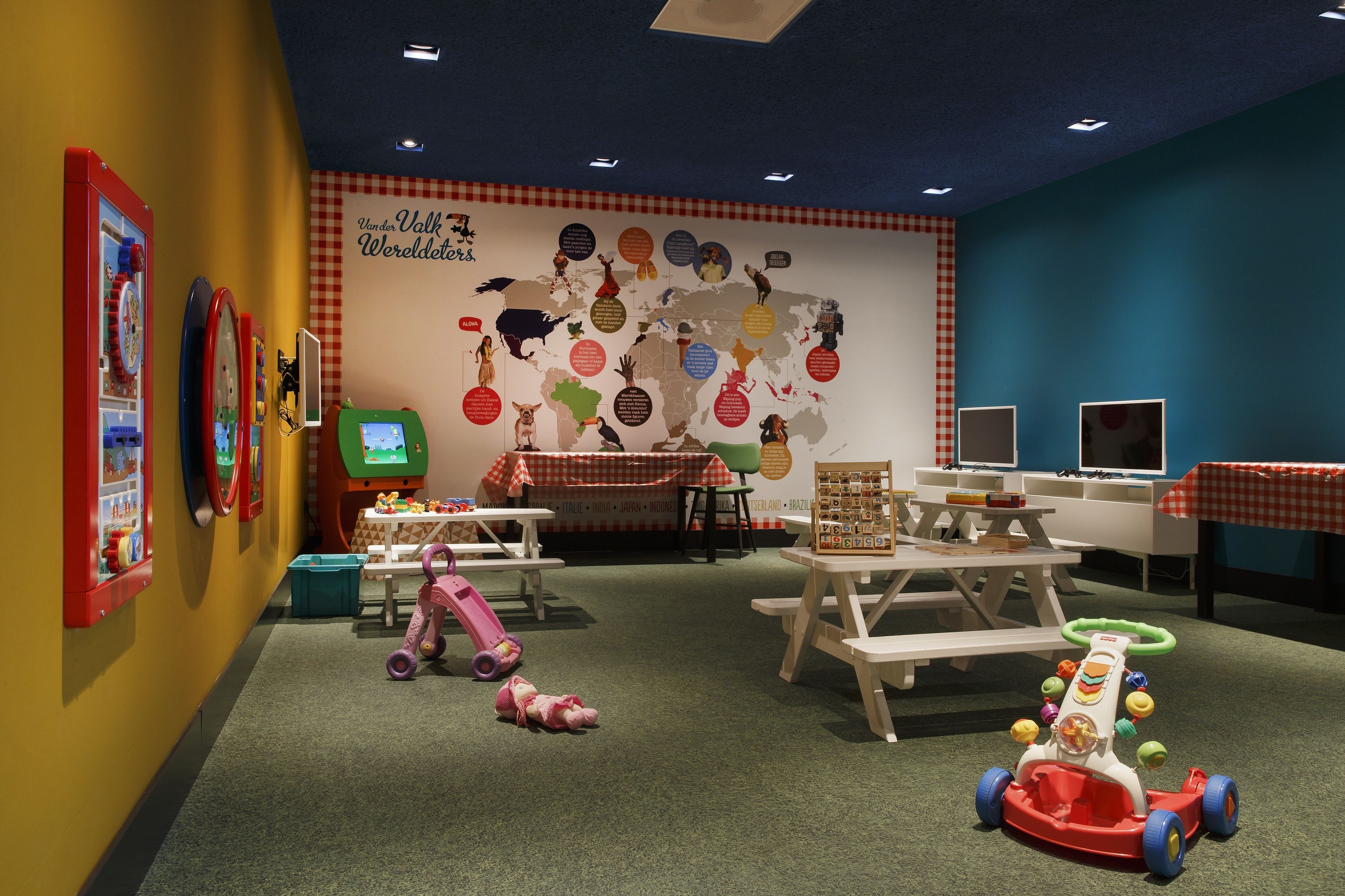 Espaço infantil com brinquedos, um mapa-múndi e cartazes educativos na parede.