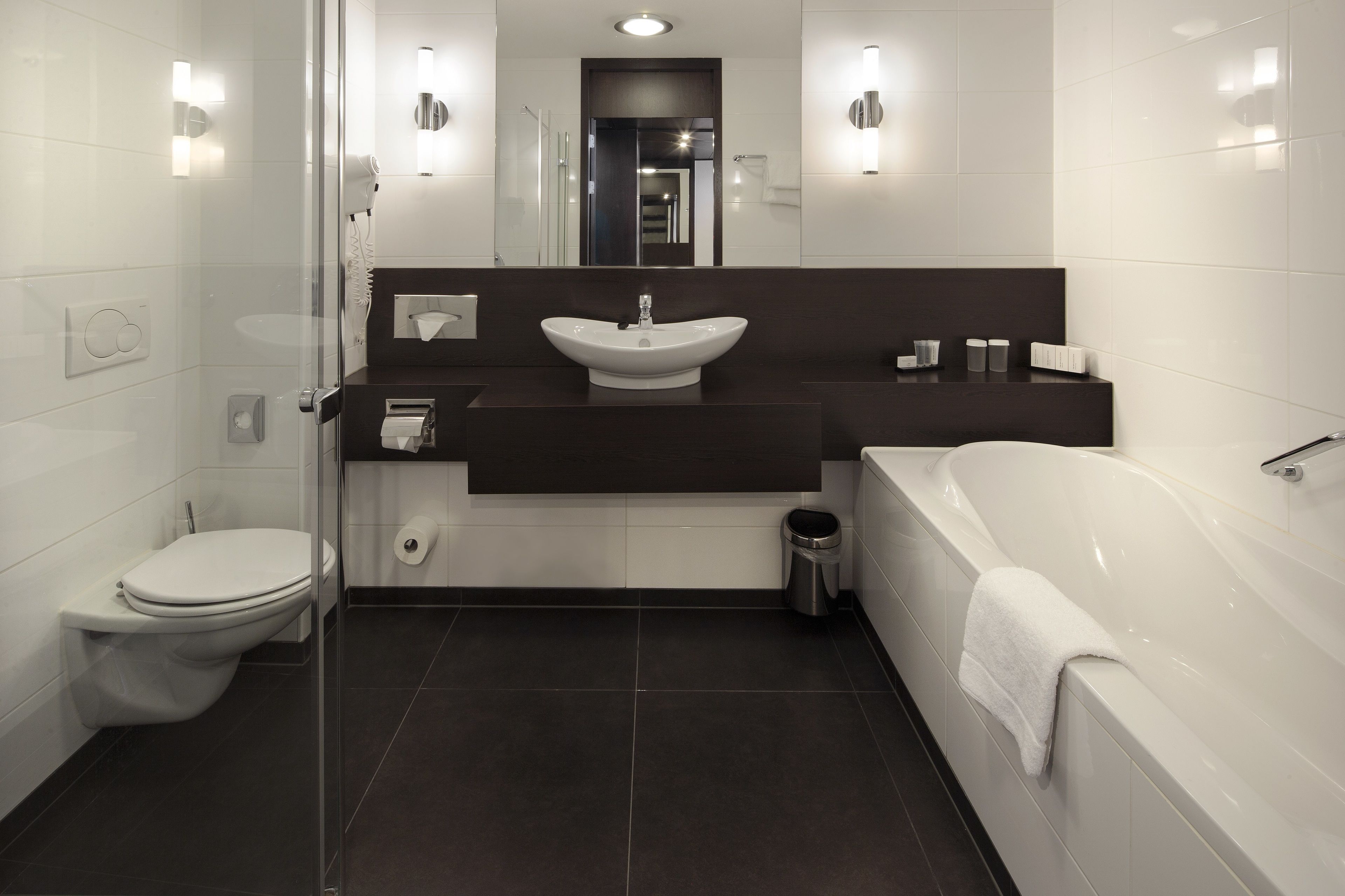 Ein modernes Badezimmer mit Toilette, Waschbecken, Badewanne und einer Duschkabine aus Glas.