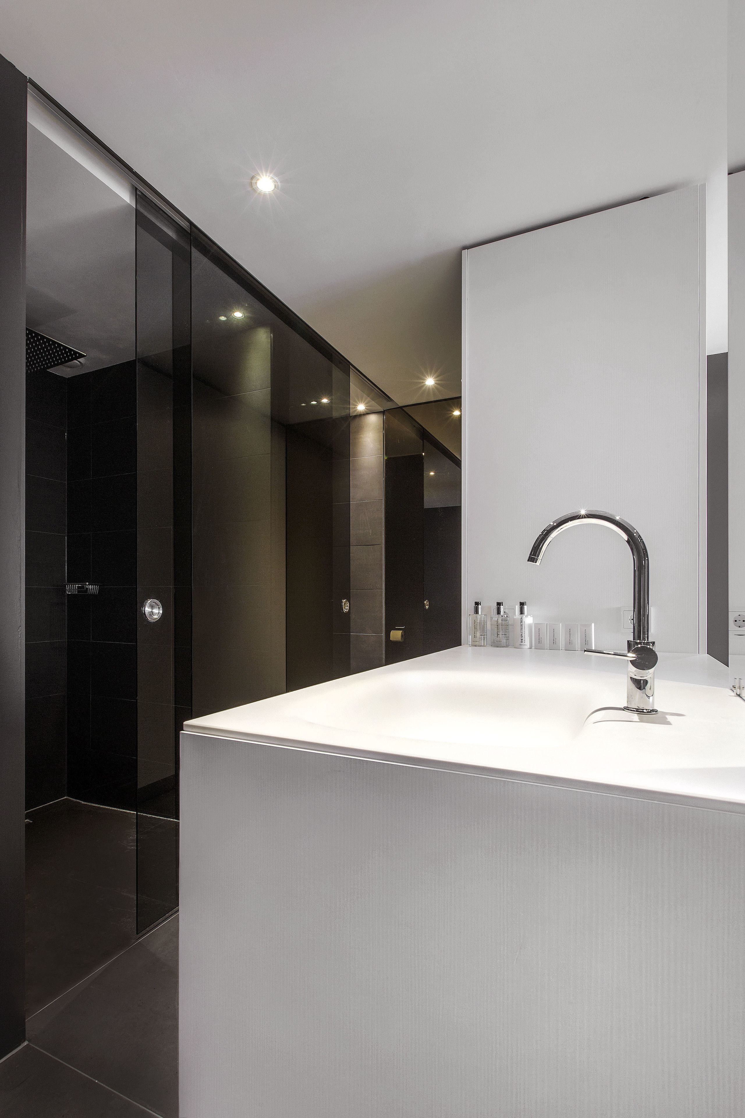 A modern bathroom with a large mirror, a sleek faucet, and a glass shower enclosure.