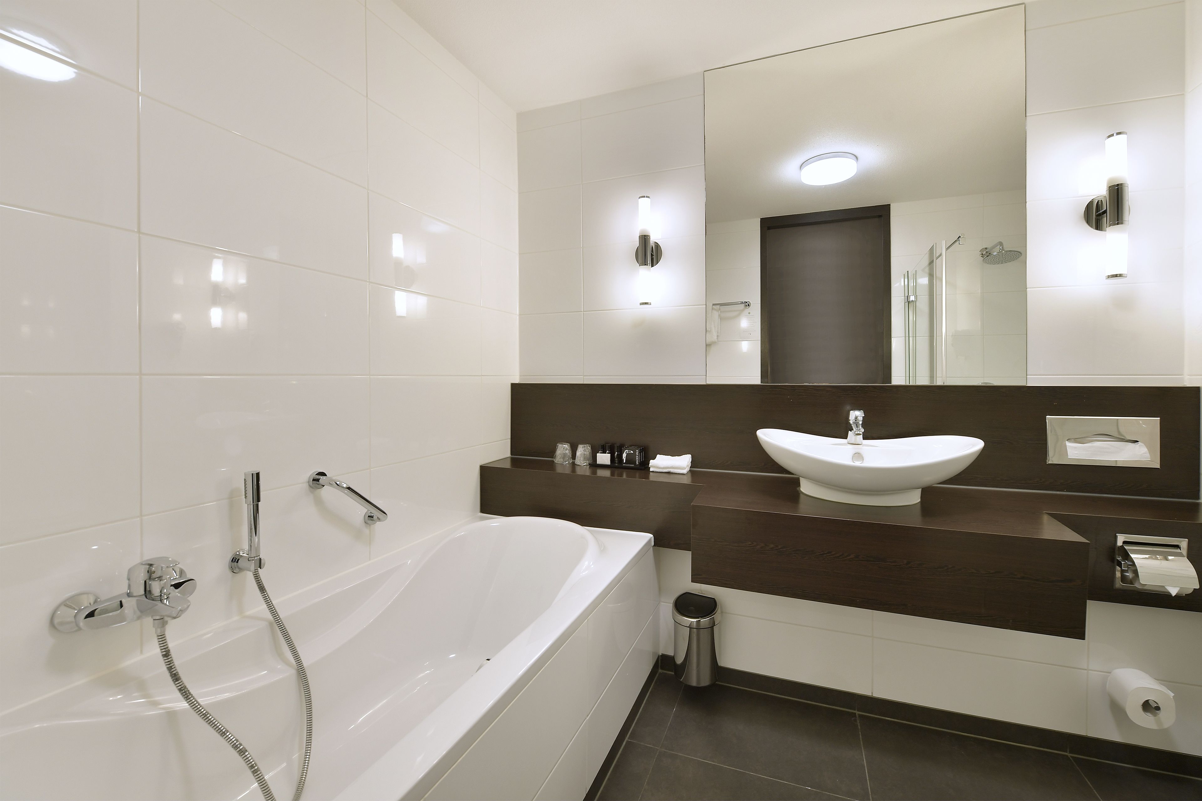 A modern bathroom with a white bathtub, a sink, and a large mirror.