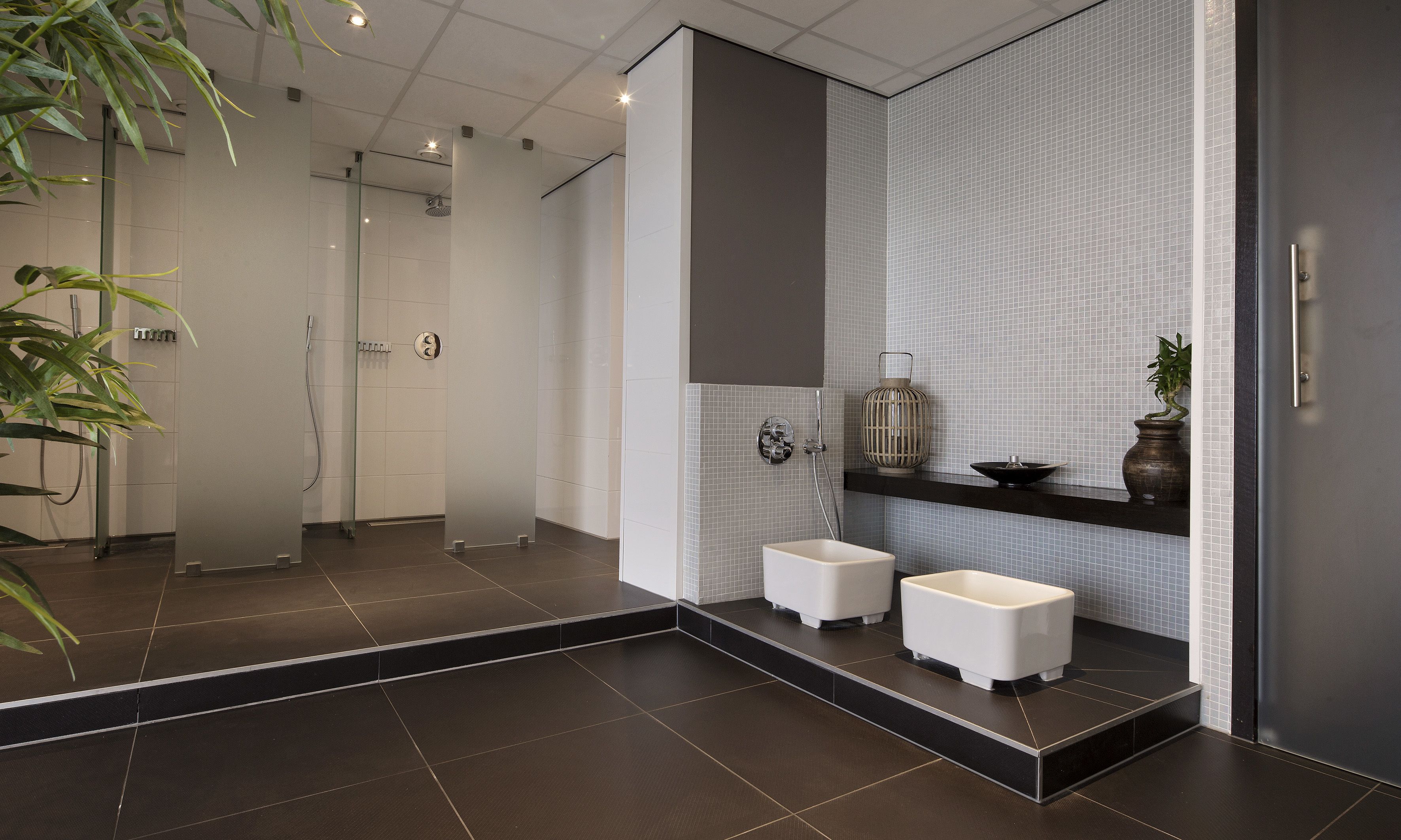 Un baño moderno con ducha de vidrio, un lavabo blanco y un espejo con revestimiento de azulejos.