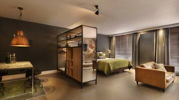 A modern bedroom with a bed, a sofa, a desk with chairs, and a wardrobe.