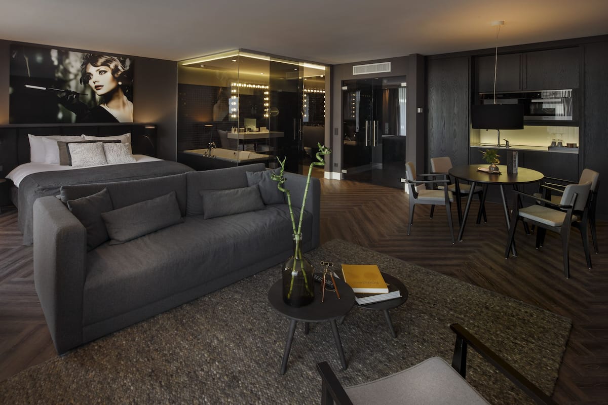 Una habitación de hotel moderna con una cama grande, un sofá, un comedor y una cocina.