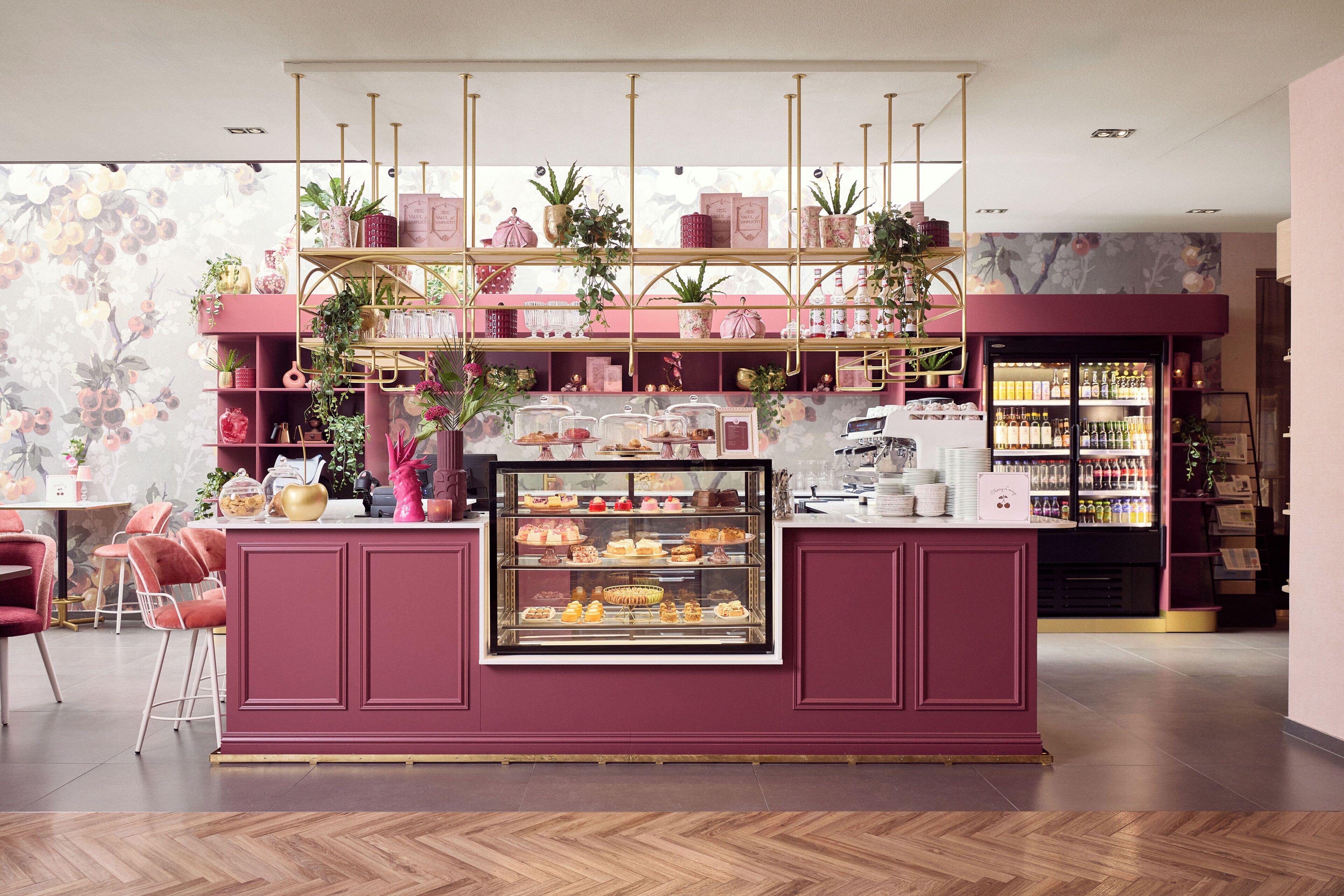 Eine Bäckereitheke mit einer Vitrine voller Gebäck, Regale mit Backwaren und verschiedenen Pflanzen.