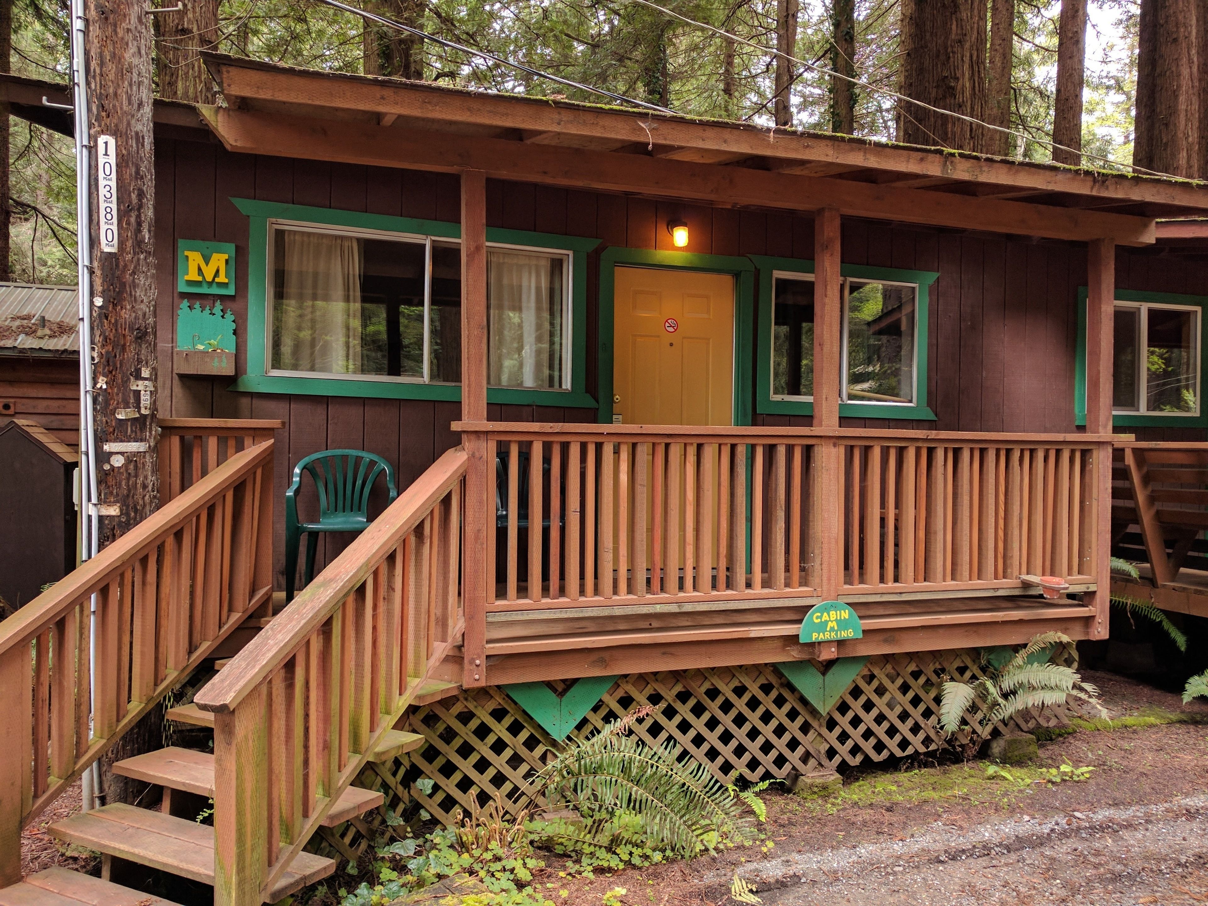 A cabin with a wooden deck, a staircase, and a sign indicating 'Cabin Parking'.