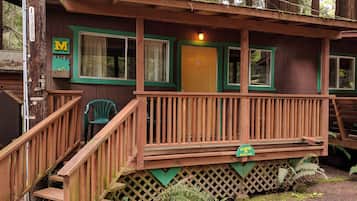 Una baita con veranda in legno, una scala e un cartello che indica 'Cabin Parking'.