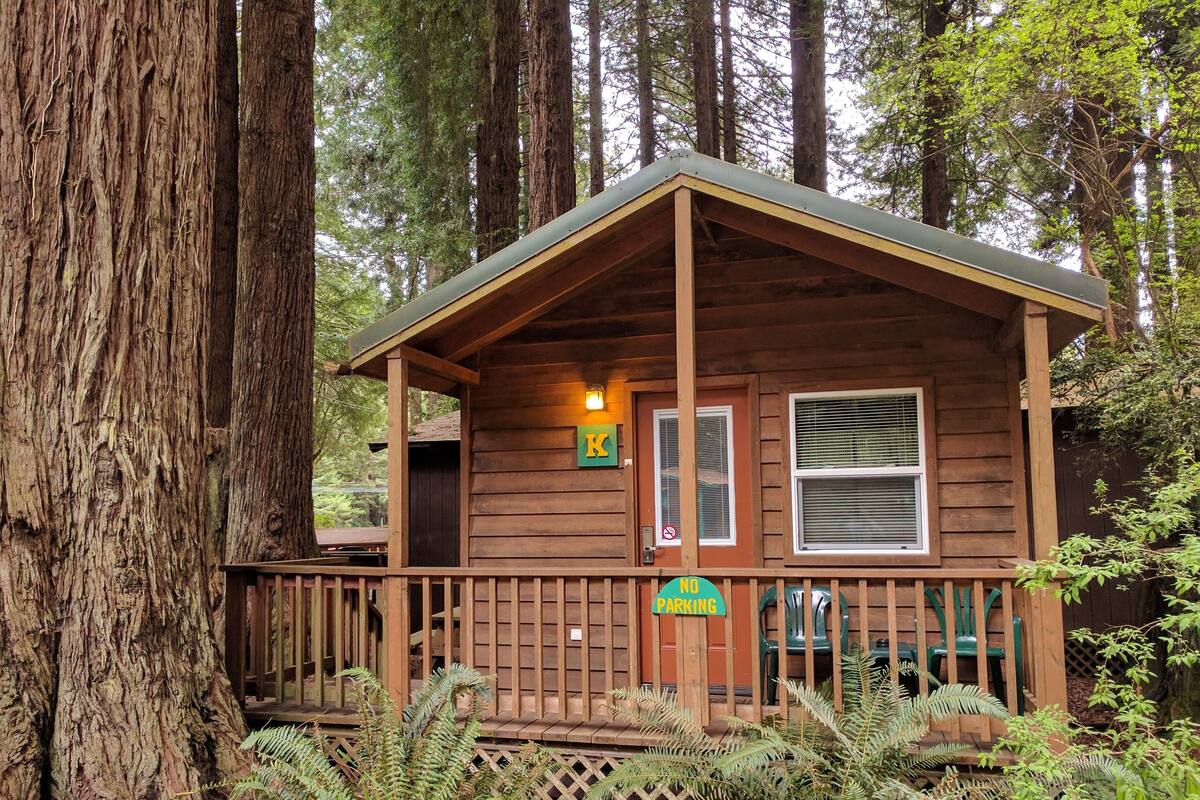 A cabin with a porch, a sign indicating no parking, and a window with blinds.