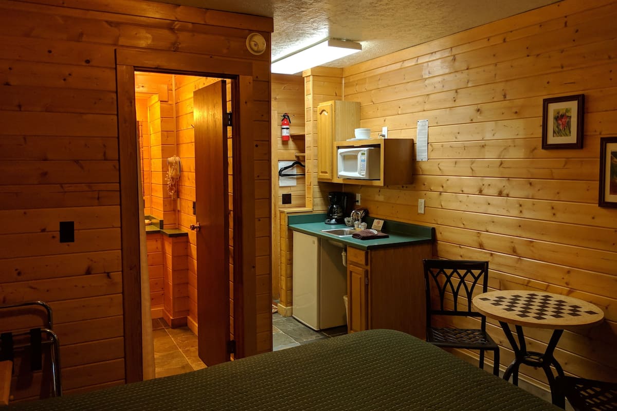 A compact room with a kitchenette, a small dining table, and a single bed.