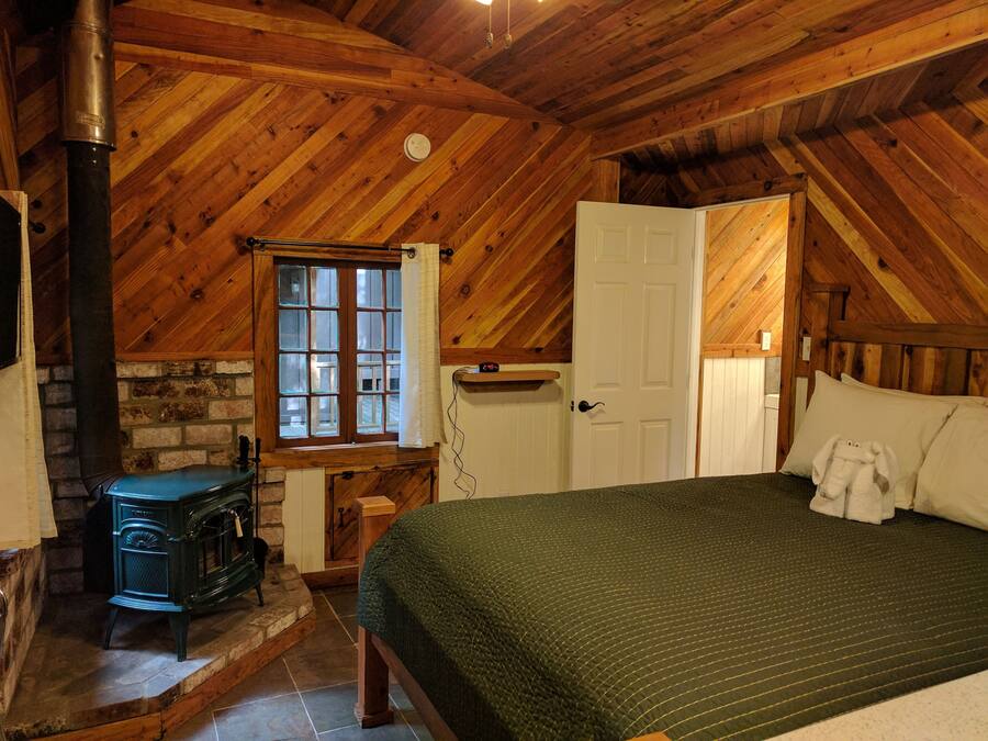 Una habitación acogedora con cama, chimenea, ventana y puerta.