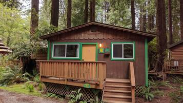 A cabin with a wooden deck, a set of stairs, and a sign indicating it is a cabin with parking.