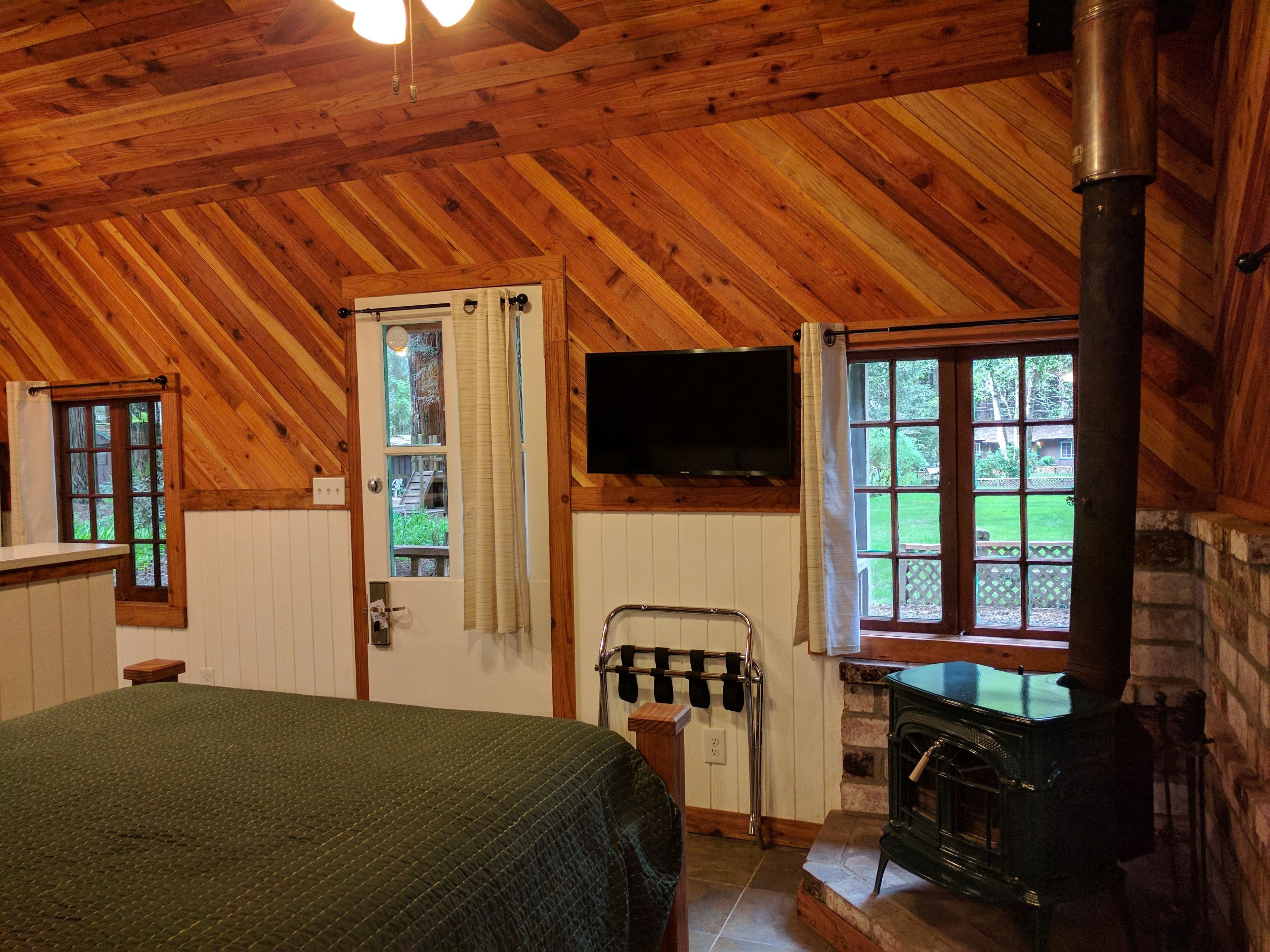 Een gezellige kamer met een houten plafond, een bed, een open haard en een televisie.