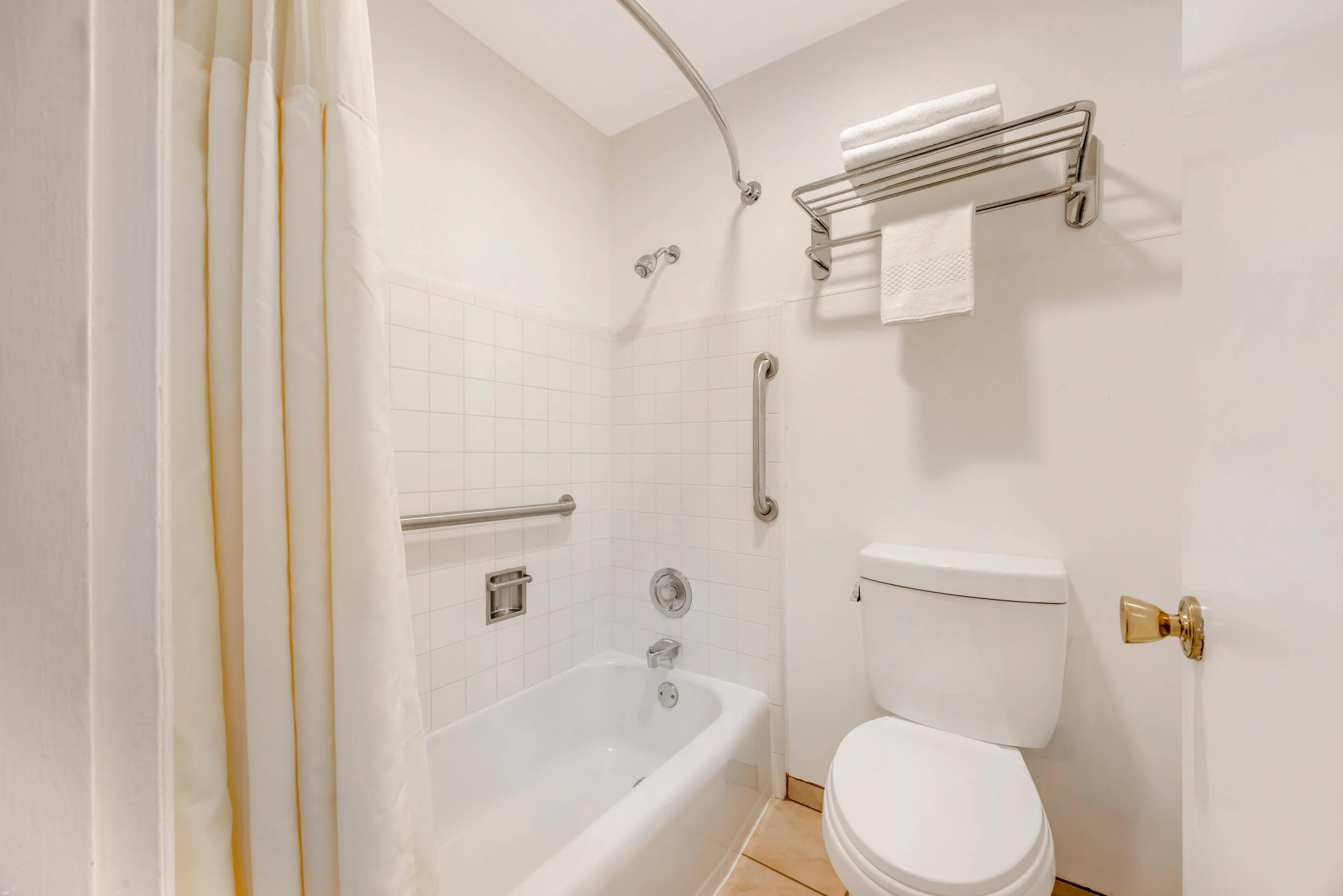 A bathroom with a white bathtub, a toilet, and a shower area.