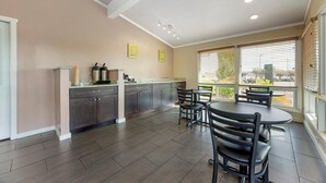 A modern kitchen with dark cabinets, a granite countertop, and a dining area with a round table and chairs. - Rodeway Inn Albany (Albany)