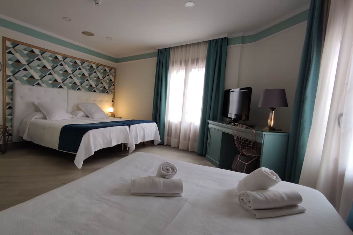 Ein Hotelzimmer mit Bett, Schreibtisch mit Fernseher und Stuhl.