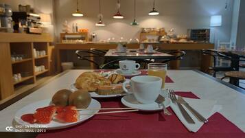 Desayuno con cruasanes, fresas y una bebida sobre la mesa.